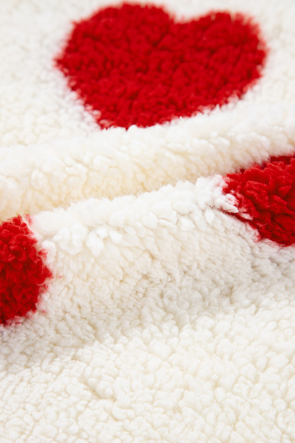 Fiery red heart shape on white sherpa plush fabric, cozy drop-shoulder crewneck texture.