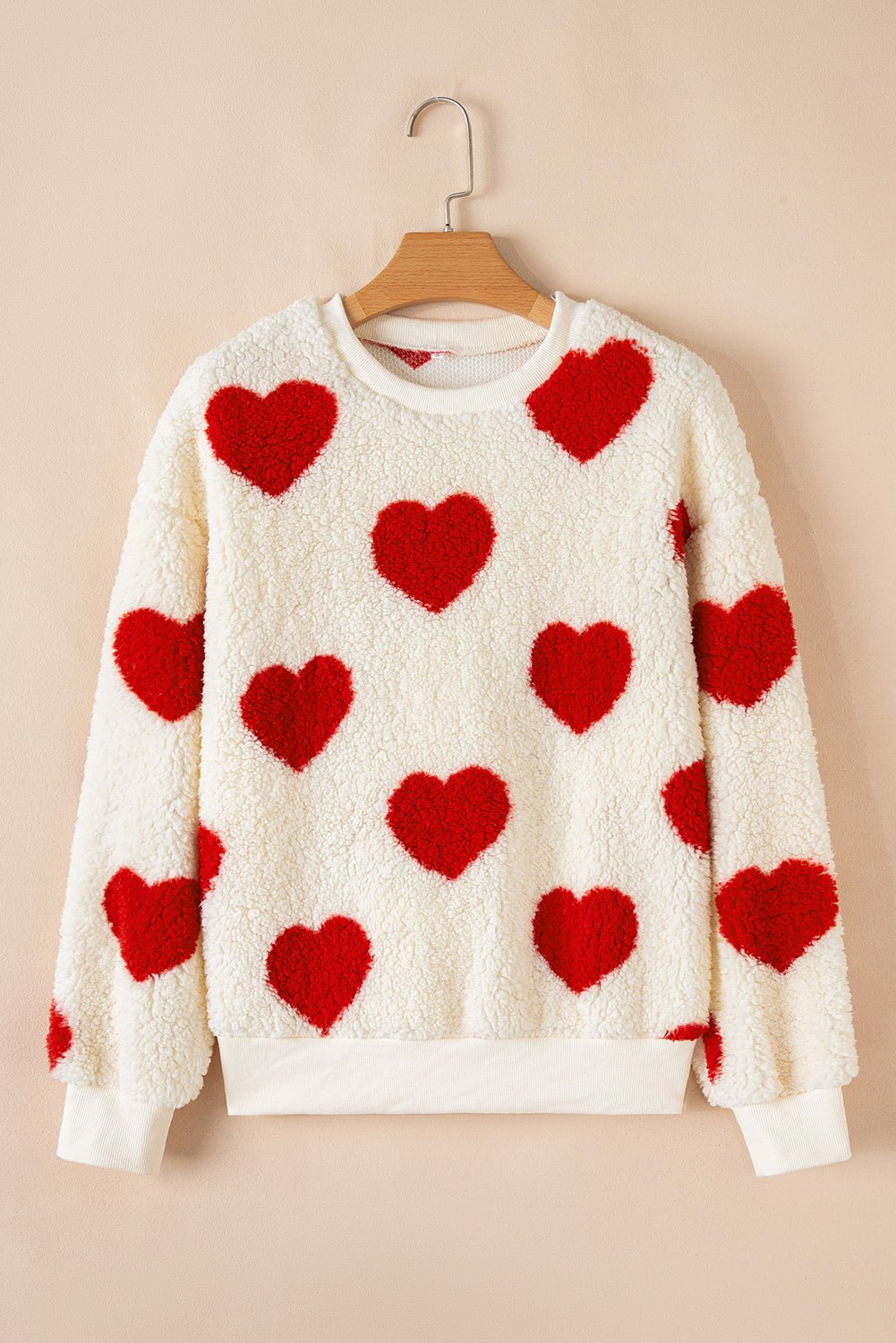 White sherpa sweatshirt with fiery red heart shapes, drop-shoulder crewneck, cozy plush texture.