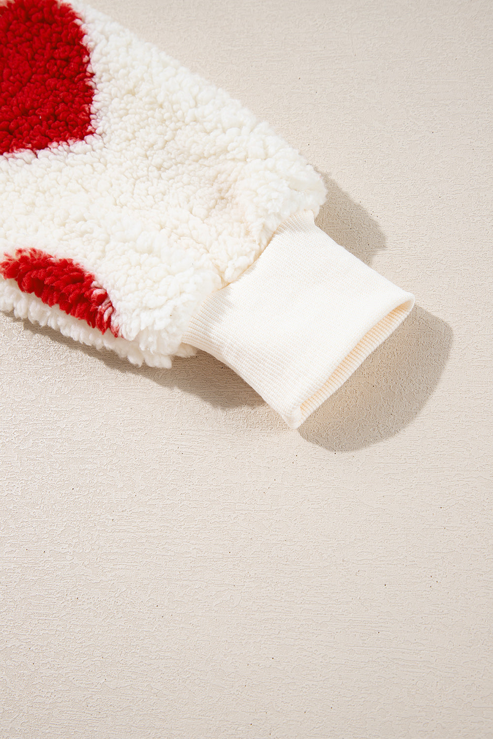 White plush sweatshirt sleeve with a red heart patch and ribbed cuff.