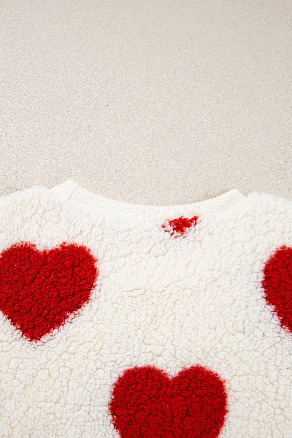 Cozy white plush fleece sweatshirt with fiery red heart shapes and drop-shoulder crewneck design.